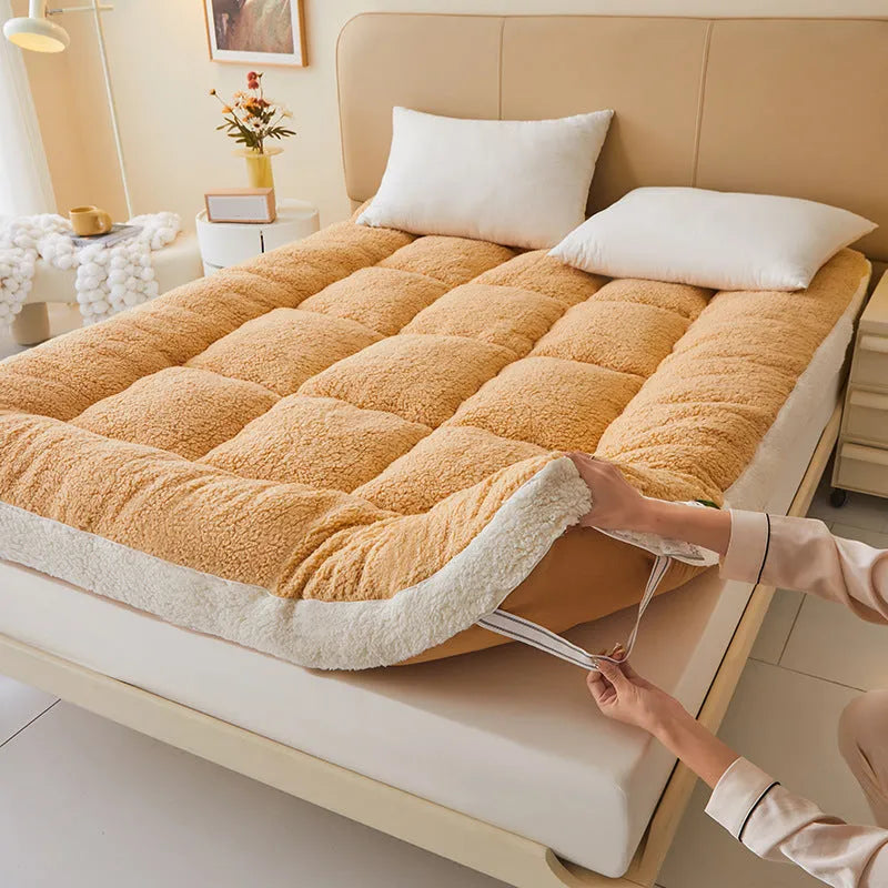 Lambswool mattress cushion with velvet cover in grey and white edge, on a bed