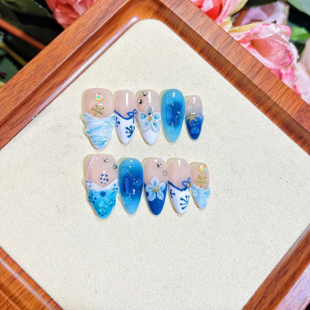 Blue hand-painted carved plastic fake nails on a clear background.