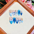 Blue hand-painted carved plastic fake nails on a clear background.