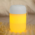 White cylindrical mini humidifier with USB cable and aromatherapy tray on a wooden desk.