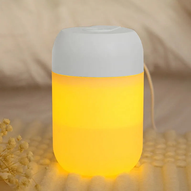 White cylindrical mini humidifier with USB cable and aromatherapy tray on a wooden desk.