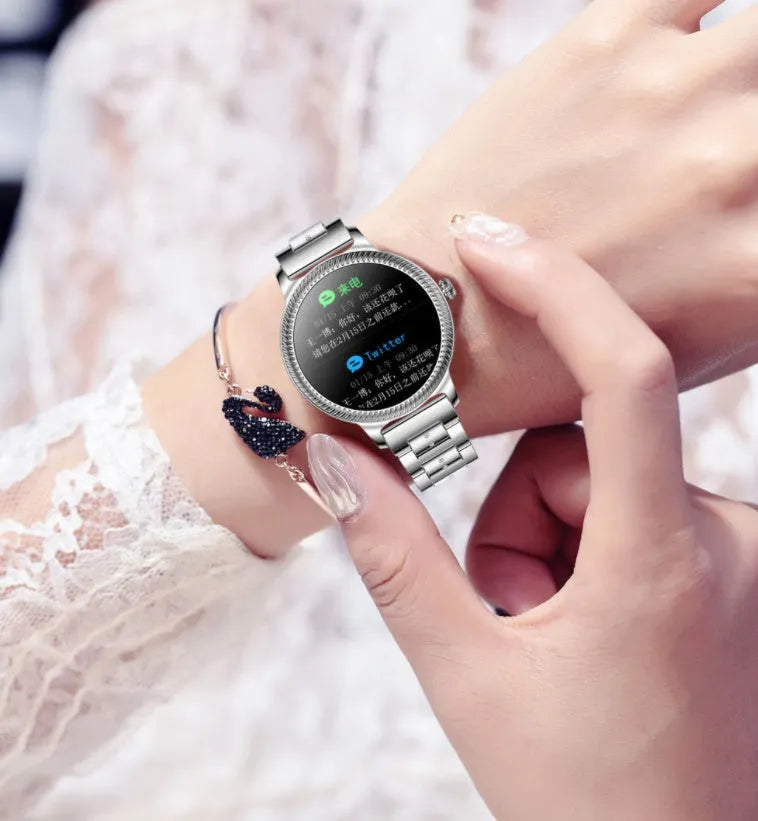 AK38 ladies smart watch with stainless steel band on a wrist, showing its 1.09-inch screen.