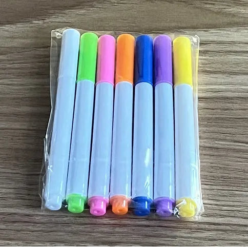 DIY acrylic message board LED night light on desk with colourful writing, USB cable, and pens