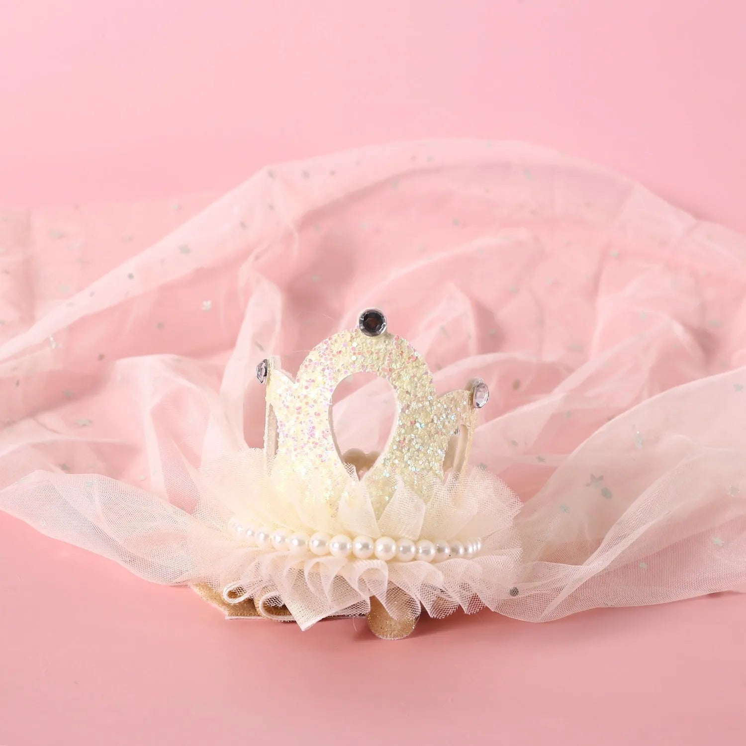 Pet cat wearing a white princess crown headdress with a beige veil accessory.
