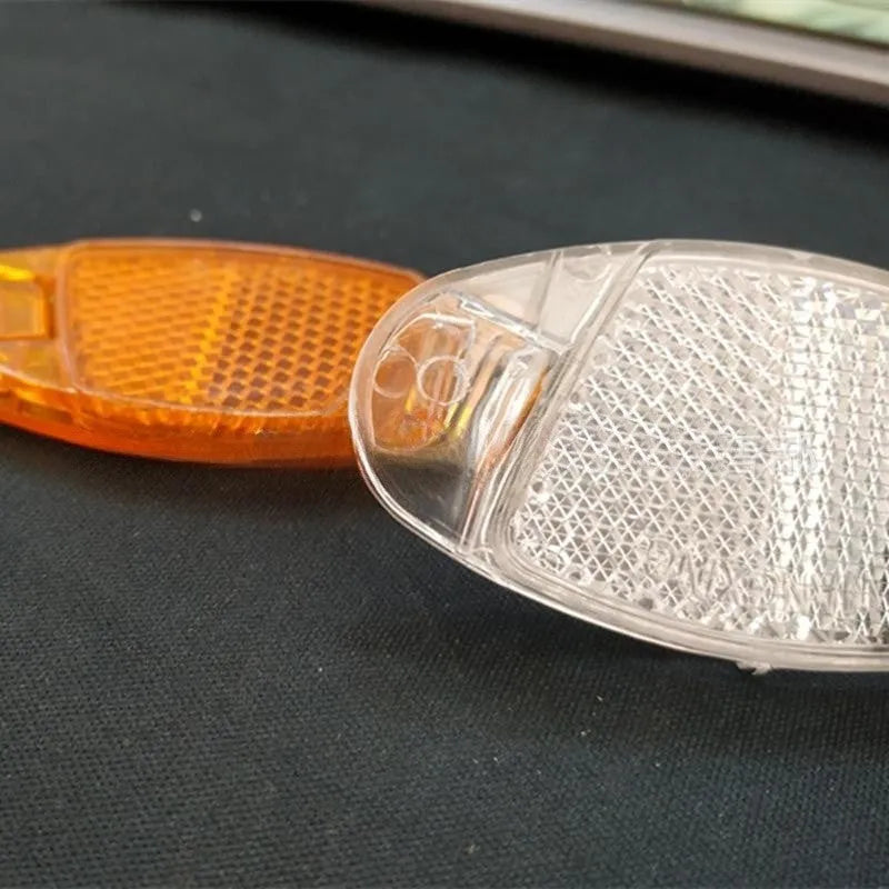 Yellow and white bicycle reflector decorations showing front and rear spoke mounting for night-time visibility