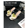 Matcha green women's high heel sandal with square toe and flower decoration on a plain background