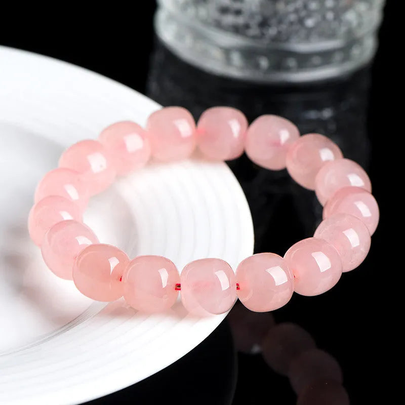 Pink natural crystal bracelet with 8x10mm barrel-shaped beads on a cord.
