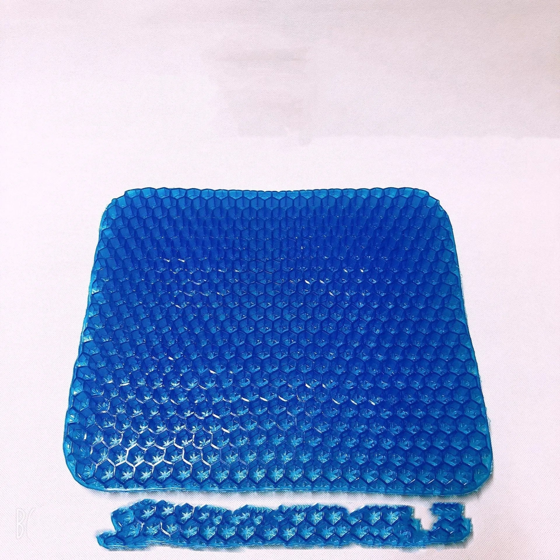 Grey gel seat cushion with honeycomb design for tailbone pain relief, shown on a car seat.