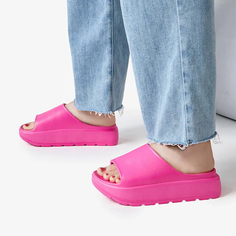 Women's beige thick-soled EVA beach slippers with fish mouth design on a wooden floor.