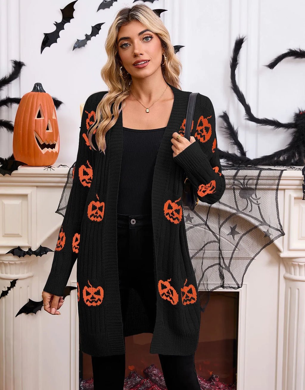 Women's black cardigan with orange pumpkin head jacquard knit pattern, shown as a medium-length coat.