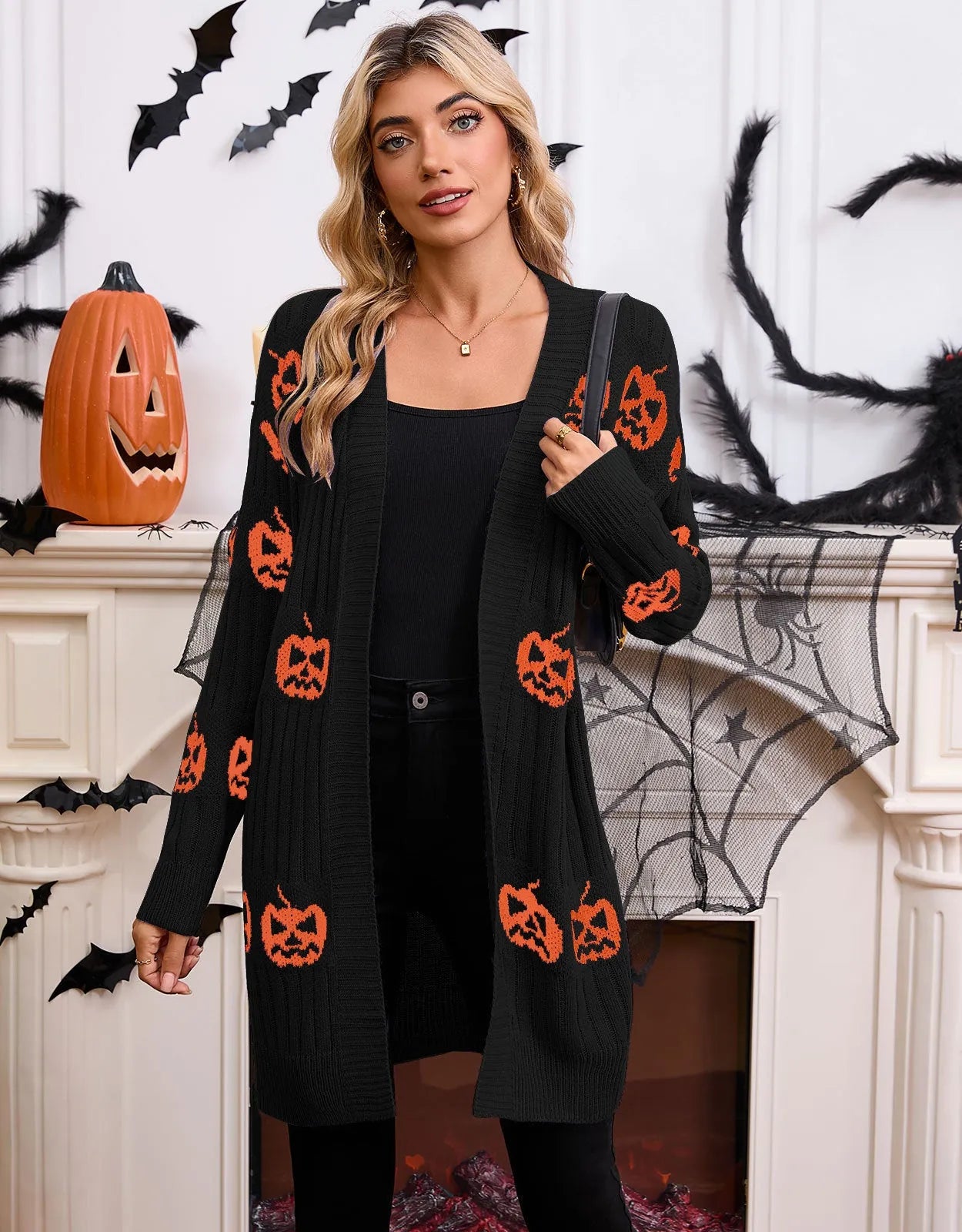 Women's black cardigan with orange pumpkin head jacquard knit pattern, shown as a medium-length coat.