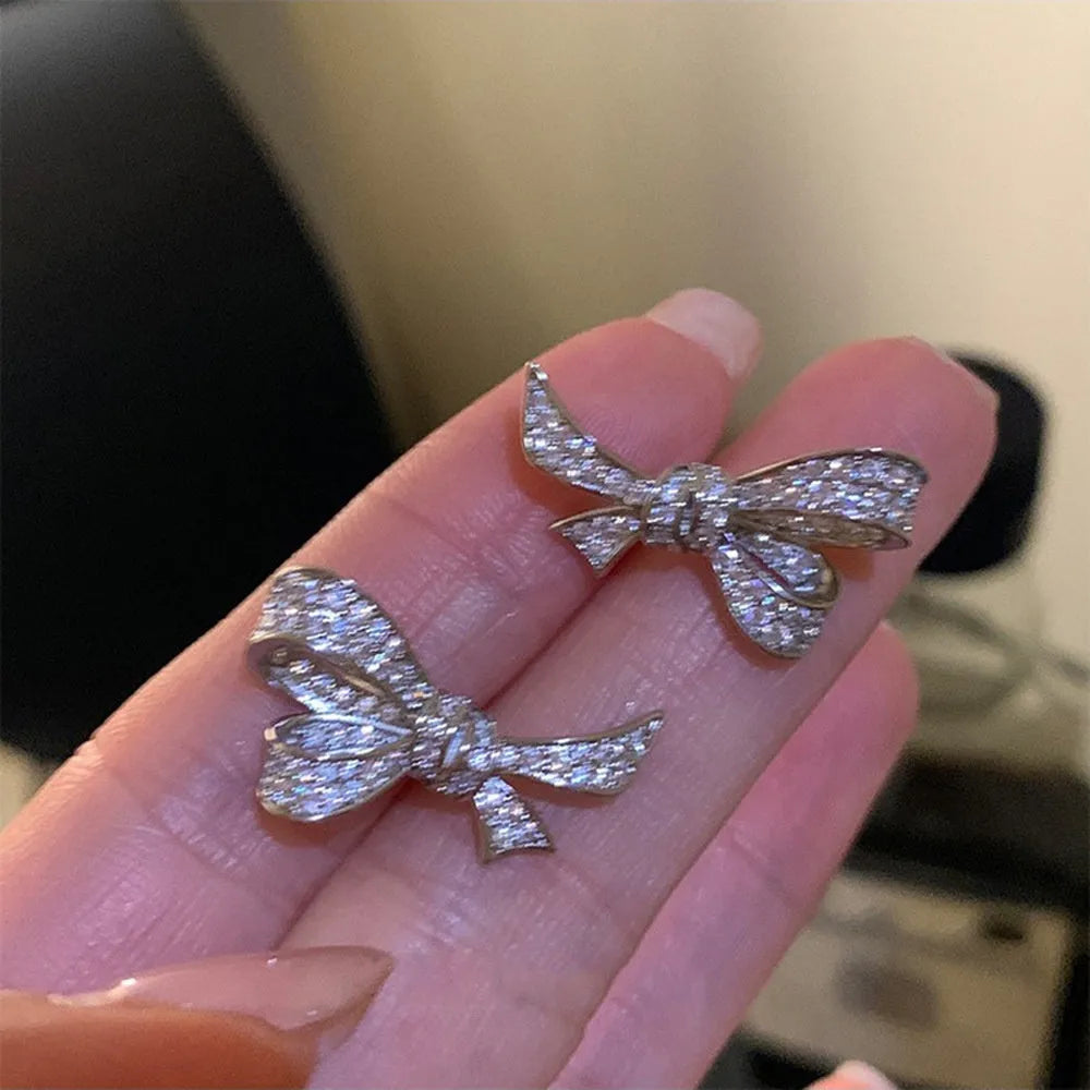 Gold miniature zircon inlaid bowknot ear stud and matching ring set on display