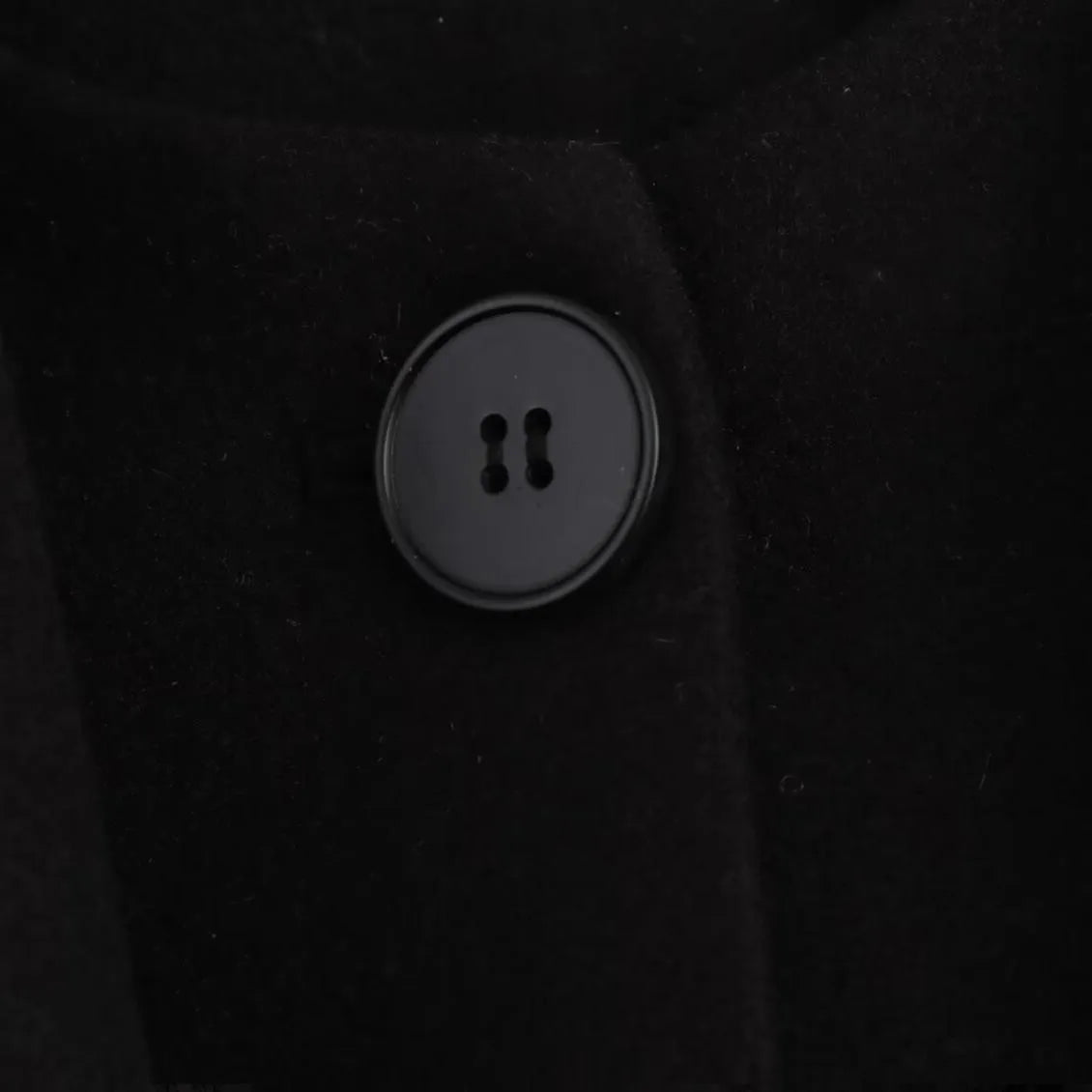 Women's long black polyester overcoat with a fluffy artificial fur collar, shown on a hanger.