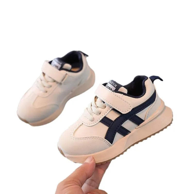 White children's sneakers with Velcro strap and textured rubber sole on a neutral background