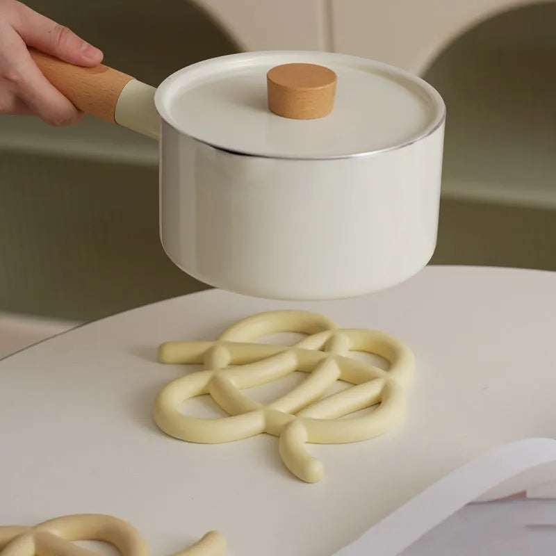 Irregular-shaped ceramic heat proof mat with hook and loop backing on a wooden table.
