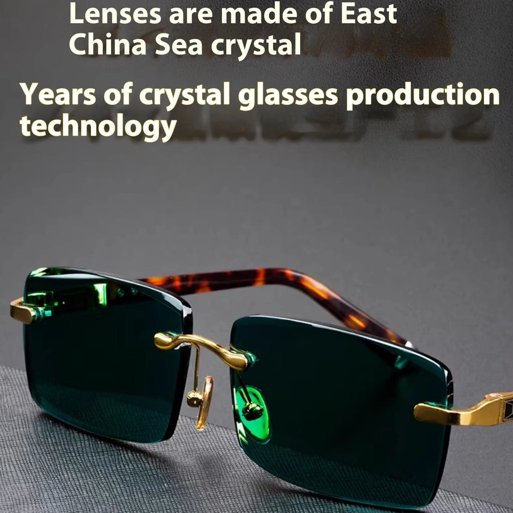 Frameless dark green crystal lens sunglasses with adjustable nose pads on a table next to their hard case.