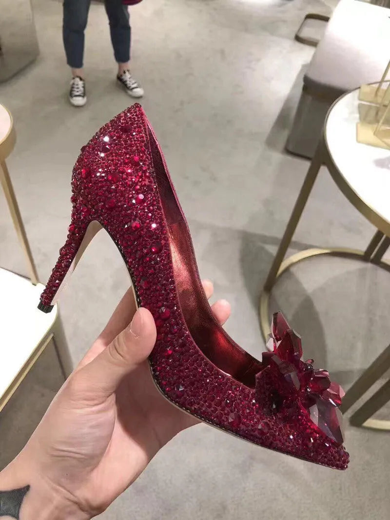 Gold women's stiletto heels with sequin upper, rhinestones, a bow, and a pointed toe.