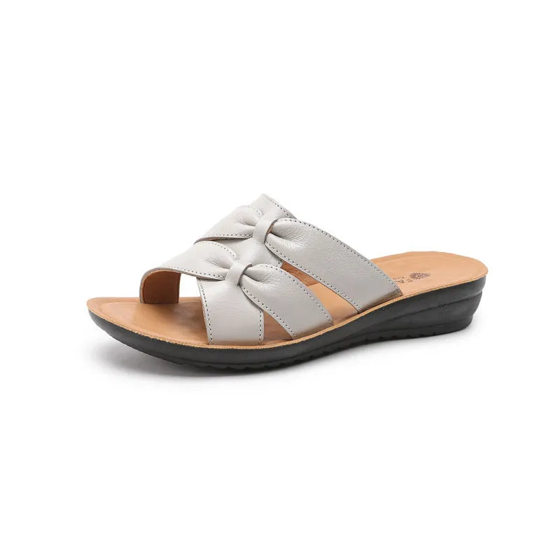 Beige women's cowhide slippers with a soft non-slip sole on a plain background