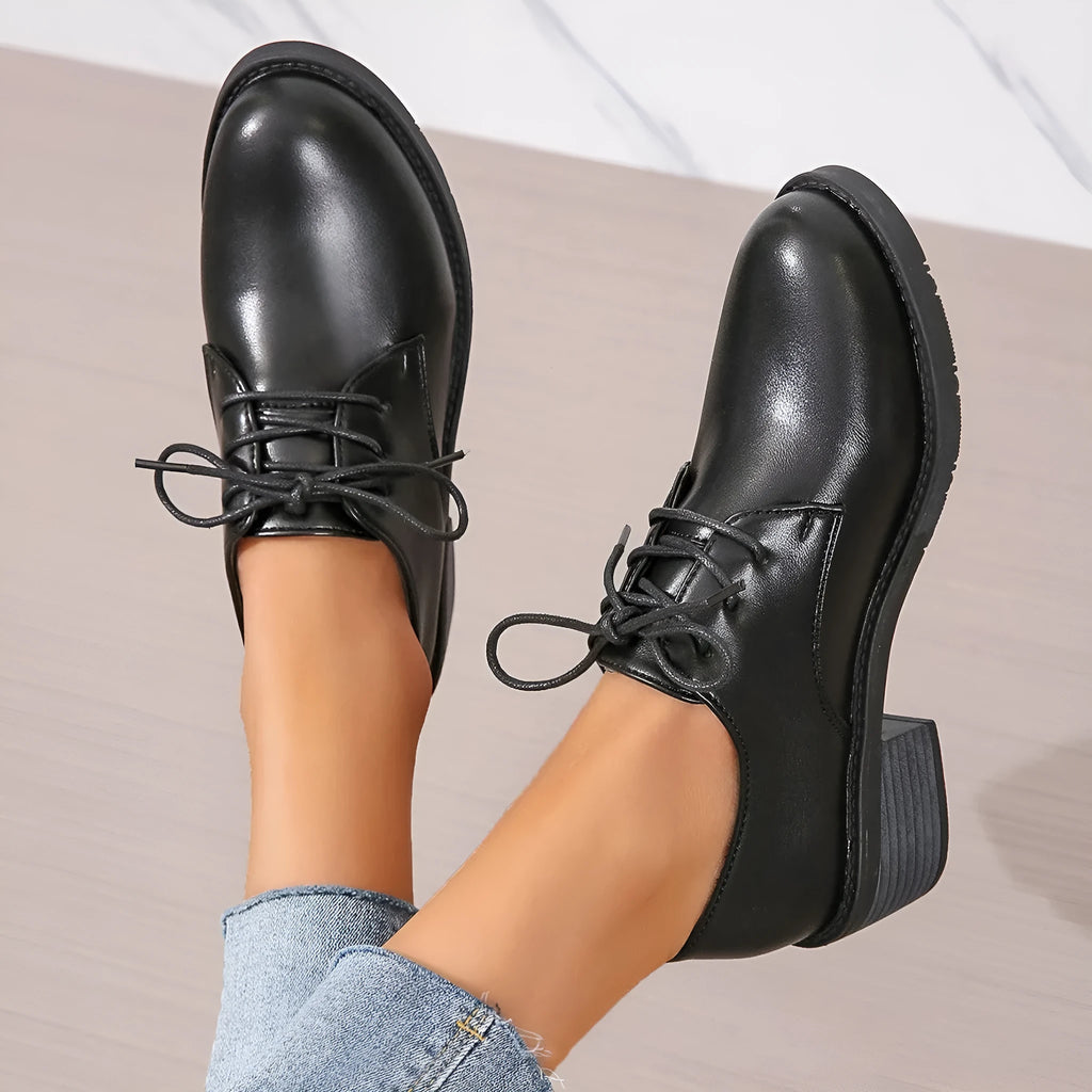Black women's low-top work shoes with a chunky mid heel and rubber sole.