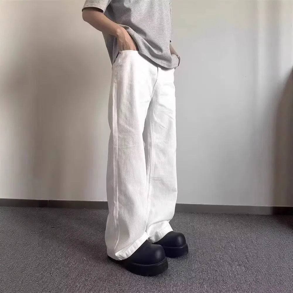 A man wearing white loose straight-leg cotton jeans with a mid-waist and zipper fly.