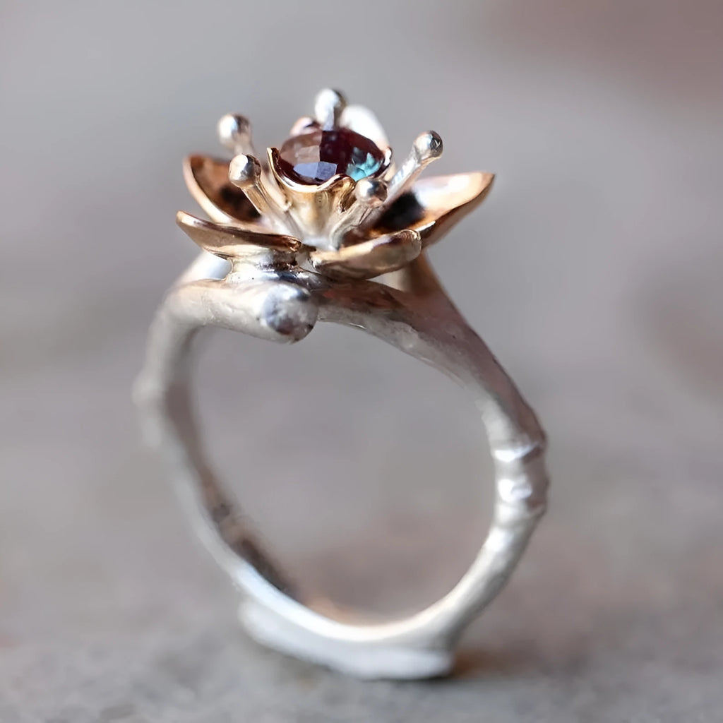 Geometric silver two-tone women's ring with open floral detail on a plain background.
