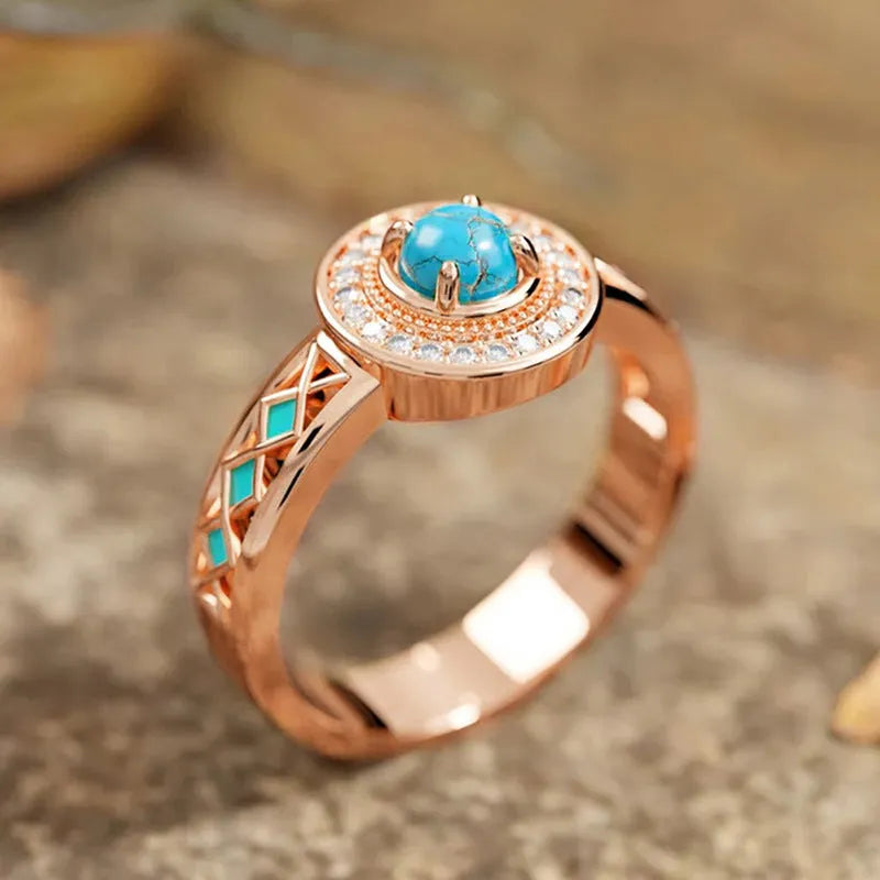 Women's turquoise ethnic geometric ring with micro inlaid zircon in rose gold coloured copper on a white background.