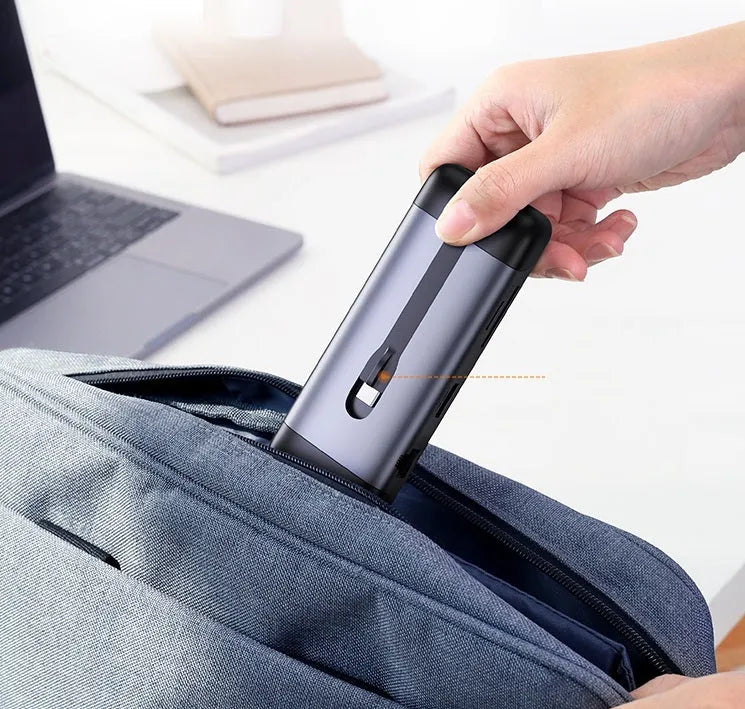 Silver USB laptop docking station with HDMI, USB 3.0, and charging ports on a desk.
