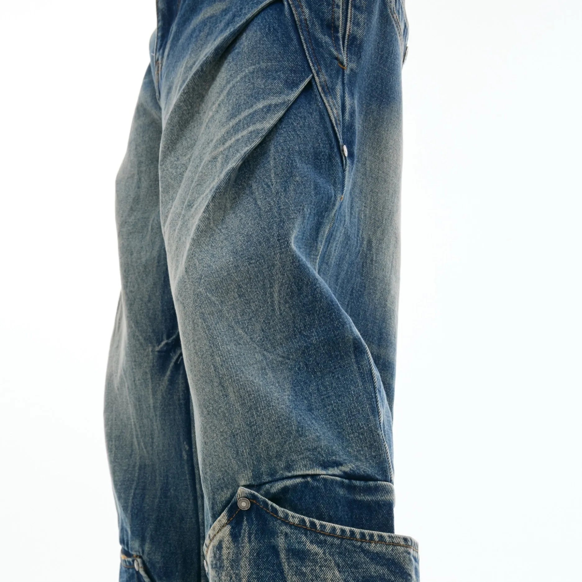 Man wearing Verdant Blue loose fit jeans with a retro washed burst pattern and a curved knife leg silhouette.