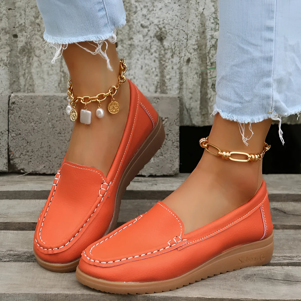 Women's black PU leather slip-on loafers with decorative stitching and a flat rubber sole.