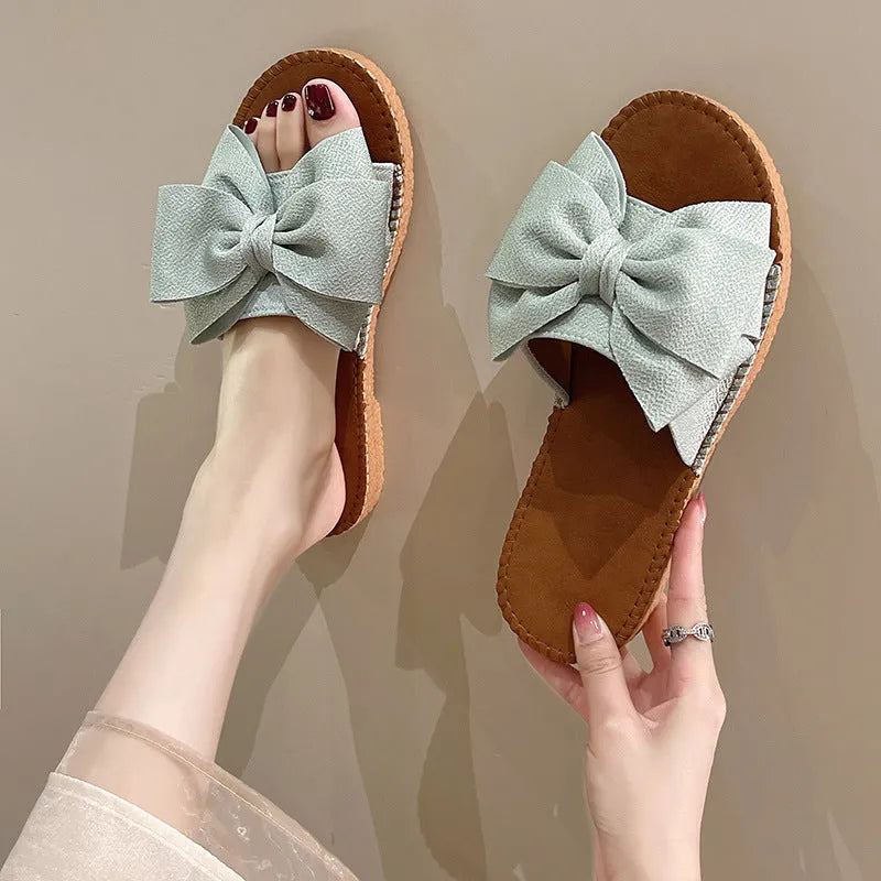 Women's beige suede slip-on sandals with a bow detail and soft rubber sole