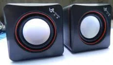 Small black square USB-powered 2.0 computer speaker on a desk.
