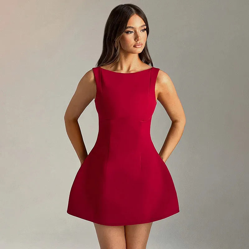 A woman wearing a black backless sling dress with a high waist and short skirt.