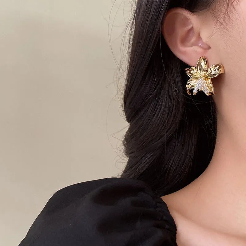 Gold H1795 metal flower earrings with an exaggerated floral design and pearl details.