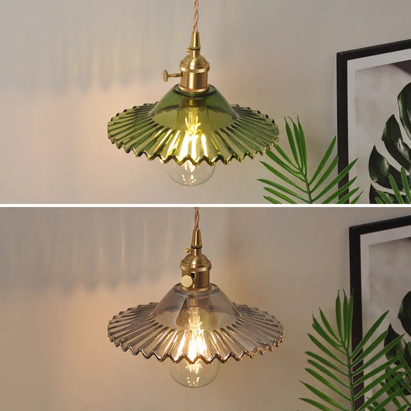 Retro brass lotus wall lamp with a smoky grey glass shade hanging on a 30cm wire beside a bed.