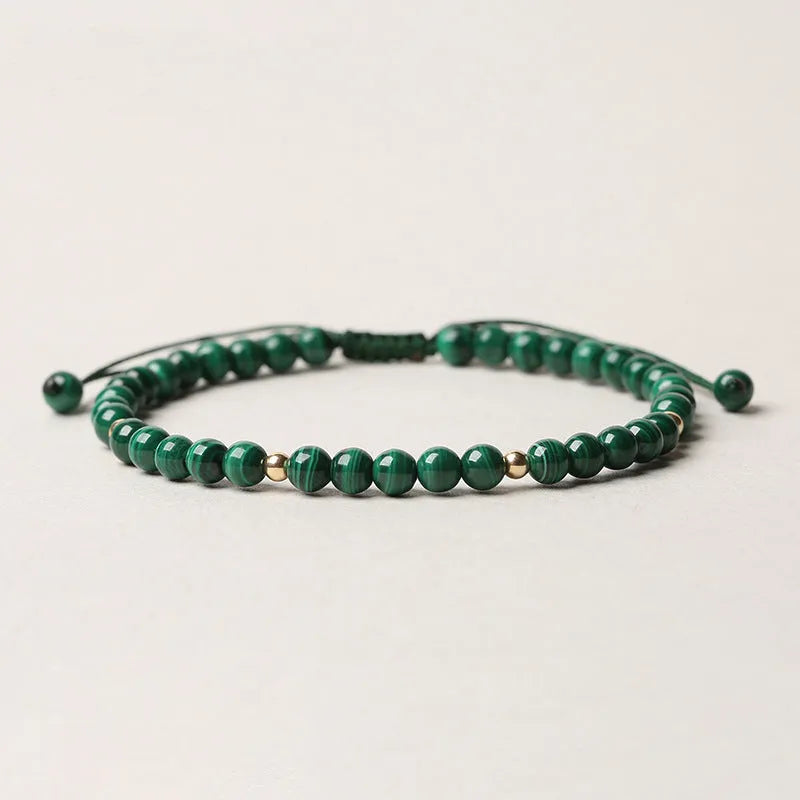 Women's malachite and gold bead bracelet with animal zodiac charm on woven strap.