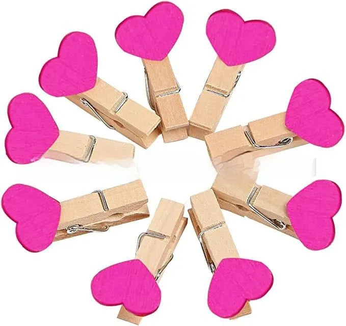 Set of five handmade solid wood heart-shaped clips in assorted colours on a wooden surface.