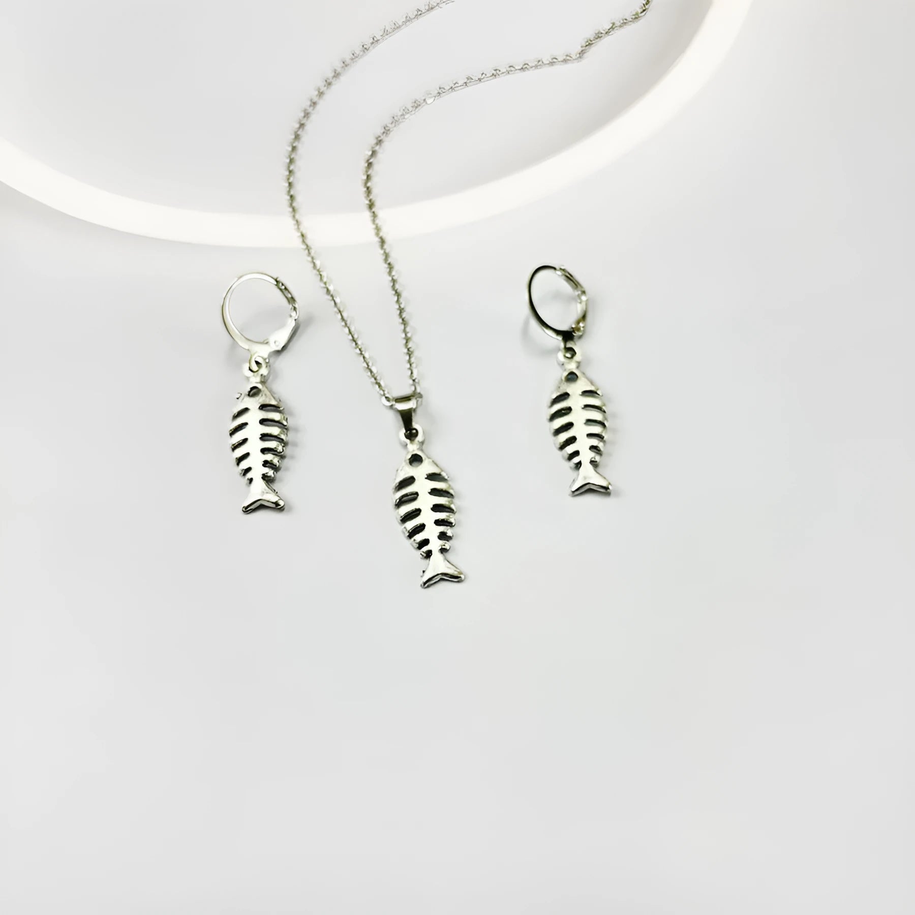 Close-up of retro-style fishbone pendant earrings on an adjustable O-chain.