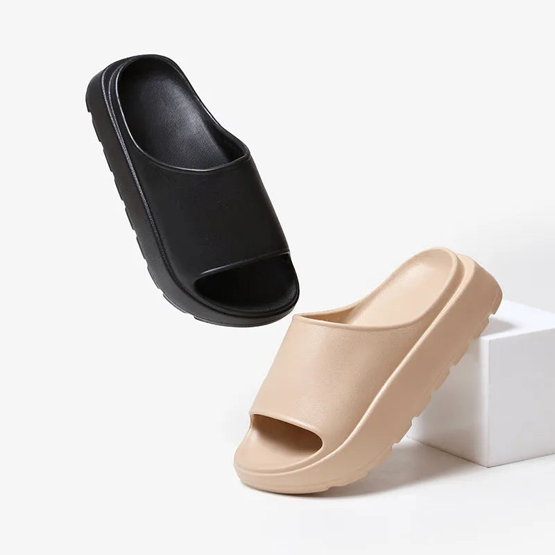 Women's beige thick-soled EVA beach slippers with fish mouth design on a wooden floor.