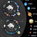 Pair of natural stone beaded bracelets with gold zodiac charms on a textile background.