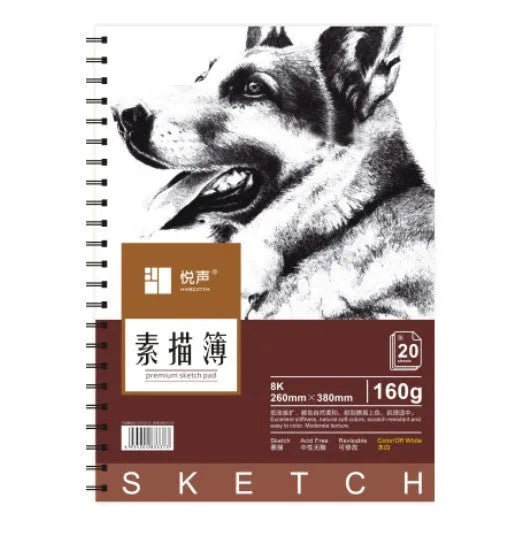 A sketchbook open on a table, showing coil binding and heavy-weight paper suitable for drawing.