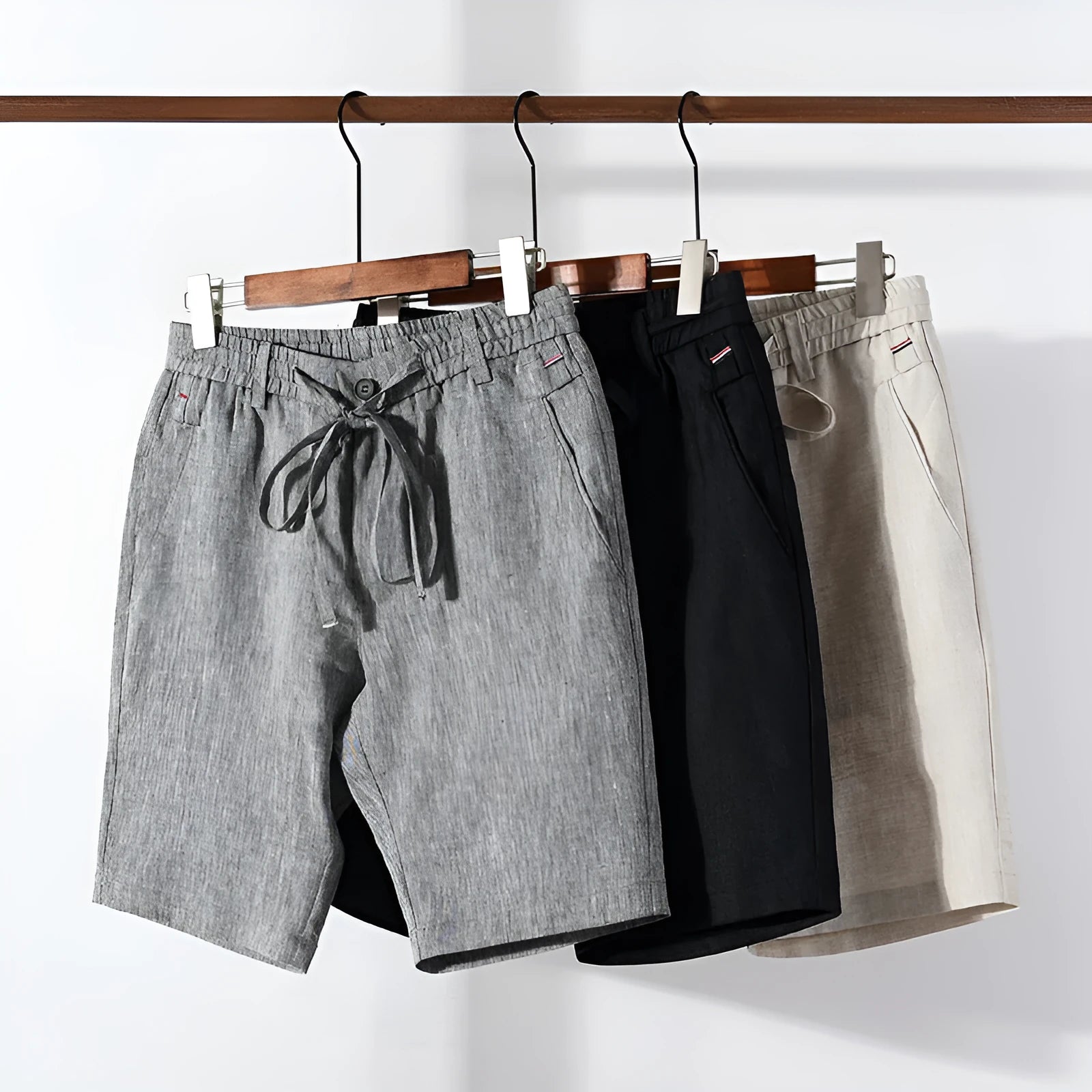 Men's 100% linen straight shorts in black, front view, mid-waist with zipper fly and pocket detail