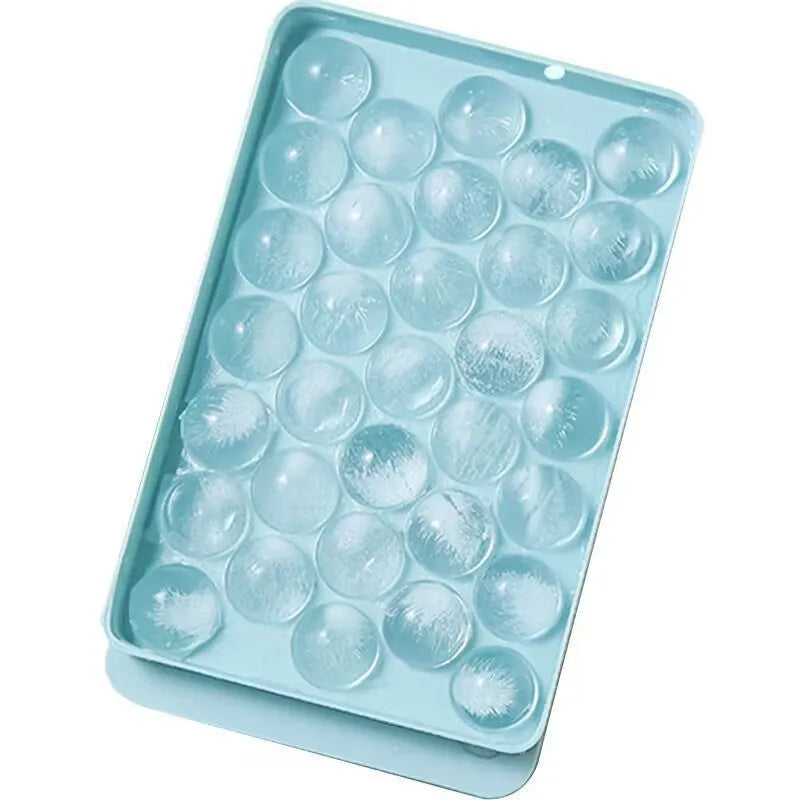 Blue lidded silicone ice cube tray making 33 round ice spheres on a kitchen counter.