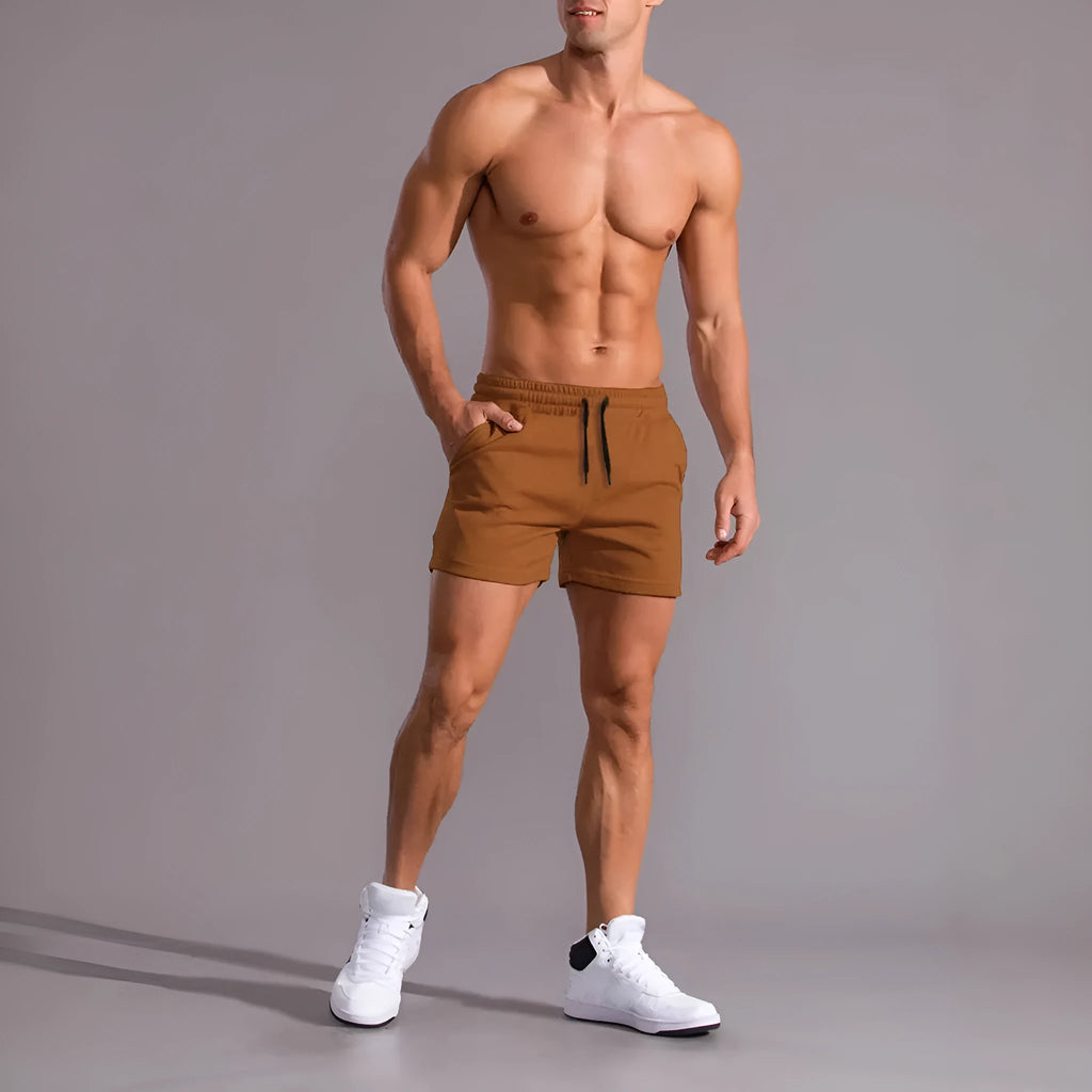 Three pairs of men's solid colour drawstring shorts in black, khaki and light brown laid flat