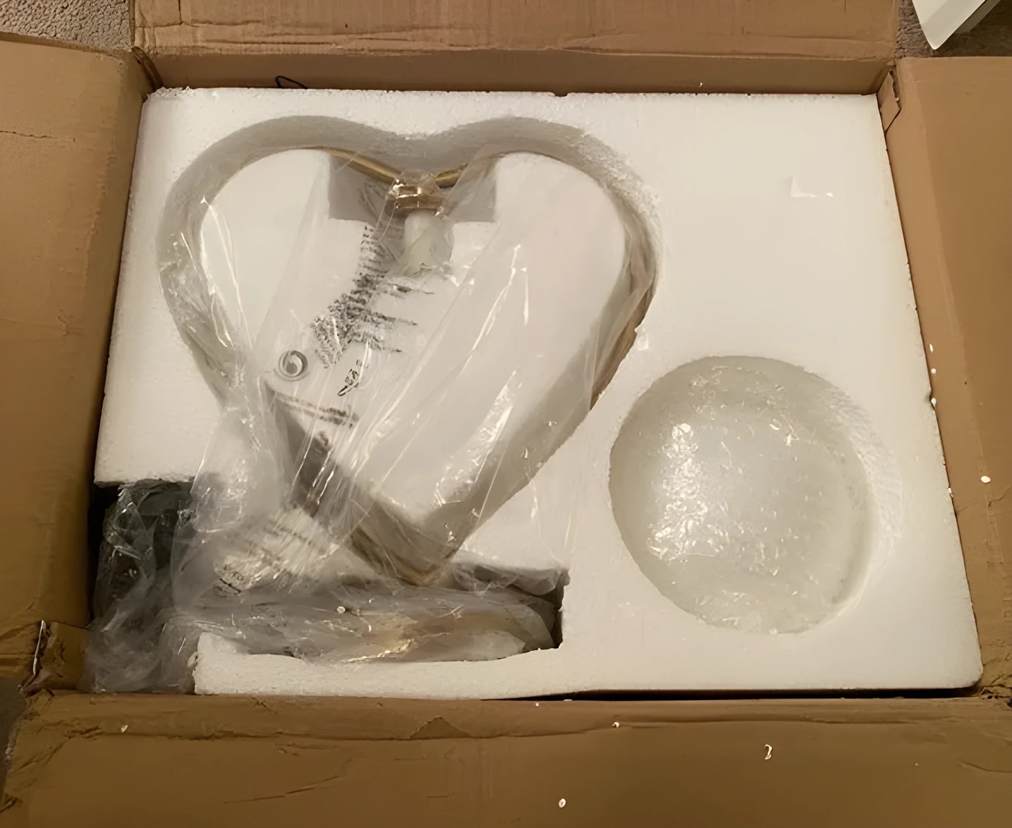 Red heart shaped plastic lamp with glowing LED light and USB cable on a table.