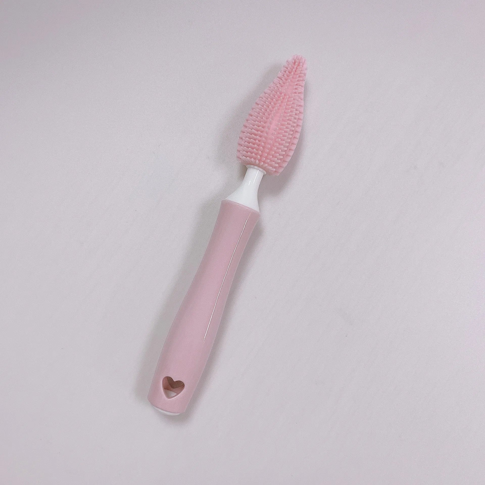 Three silicone baby bottle brushes in blue, pink, and yellow with straw scrubber on white background