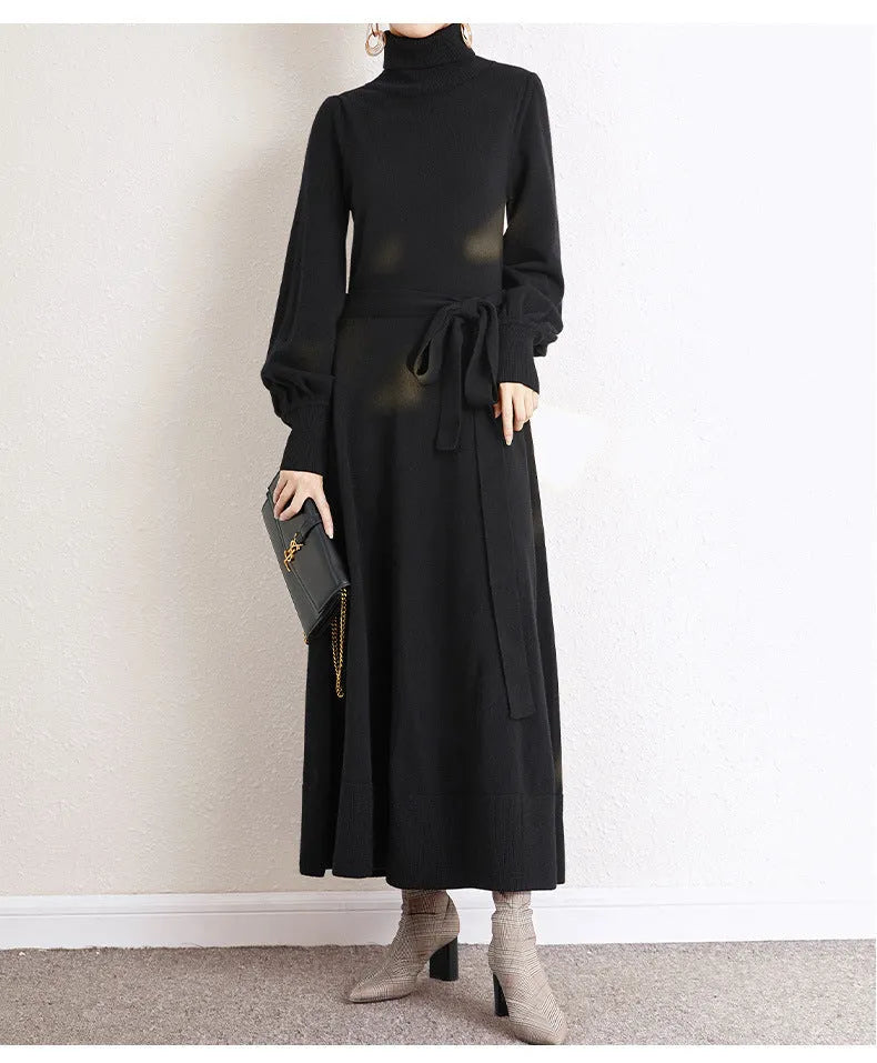 A woman wearing a rose red turtleneck knit dress with long sleeves, an elastic waist, and a loose mid-length hem.