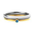 A geometric titanium steel ring with a December birthstone and gold-coloured handle on a plain background.