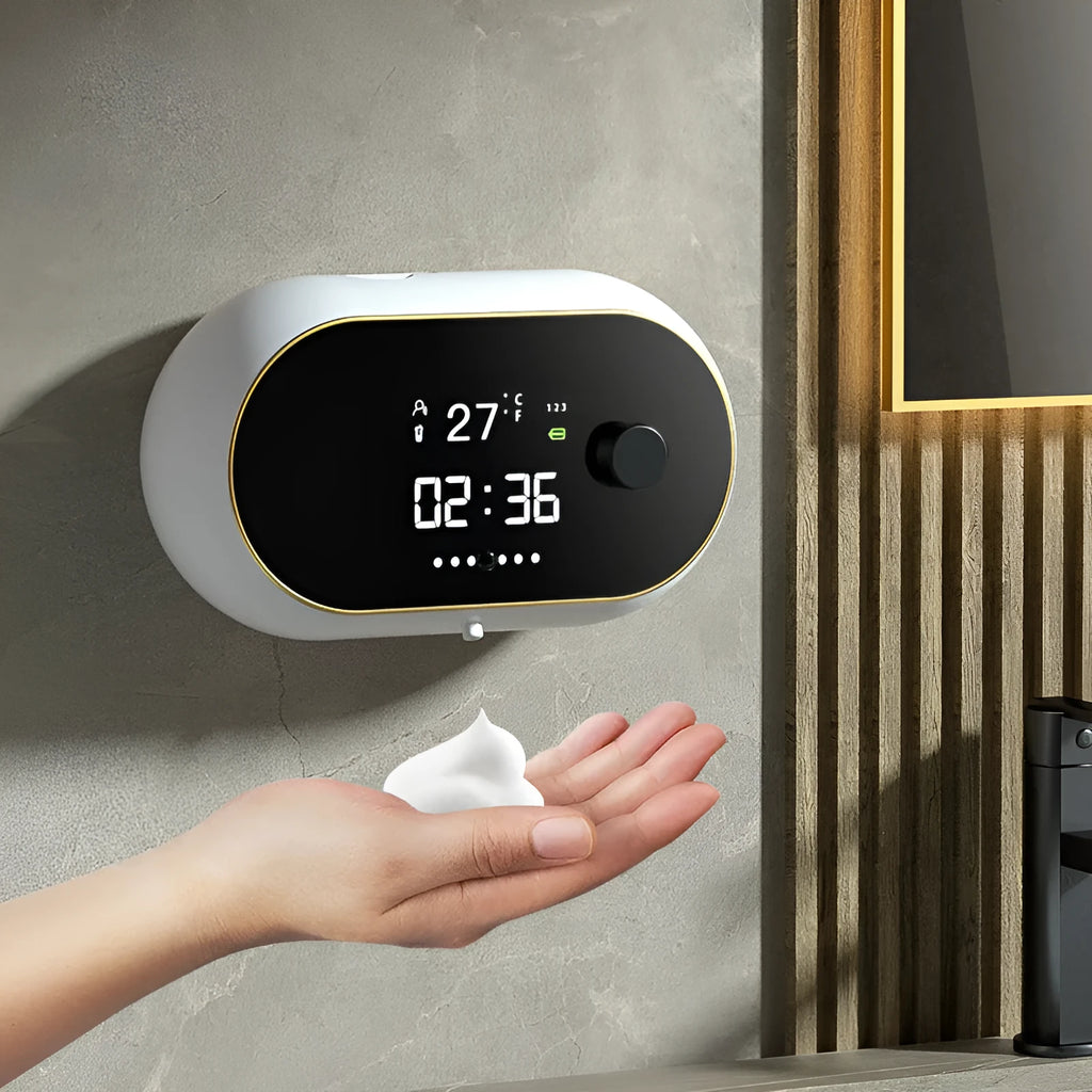 White automatic wall-mounted hand sanitiser dispenser with USB cable on a bathroom wall.
