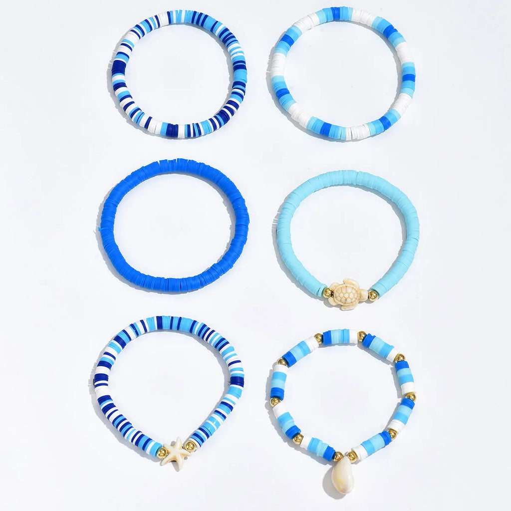 Six handmade Bohemian blue polymer clay bracelets with shell designs and geometric shapes arranged together