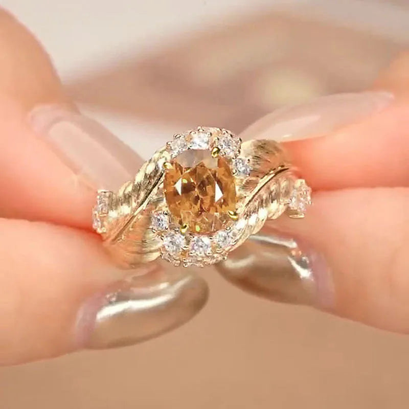 Gold feather embossed women's ring with a yellow zircon stone on a geometric copper band.